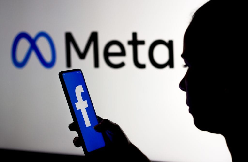 March 16, 2022, Brazil. In This Photo Illustration, A Woman Holds A Smartphone With The Facebook Logo Displayed On The Screen With The Meta Platforms Logo Displayed In The Background.